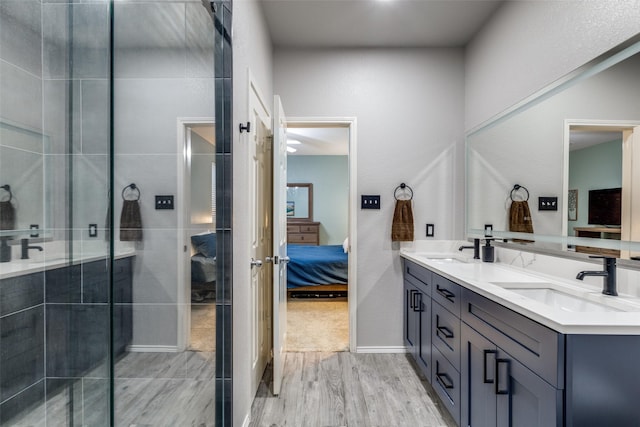 ensuite bathroom featuring connected bathroom, a shower stall, a sink, double vanity, and wood finished floors