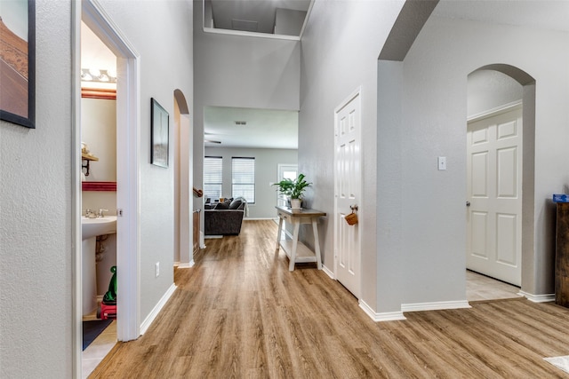 corridor featuring wood finished floors, baseboards, and arched walkways