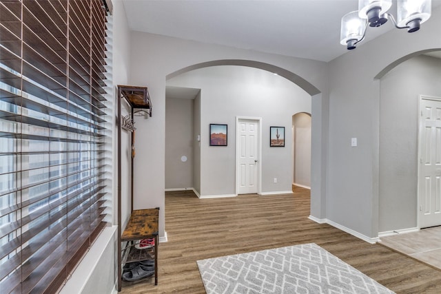 entryway featuring an inviting chandelier, wood finished floors, baseboards, and arched walkways