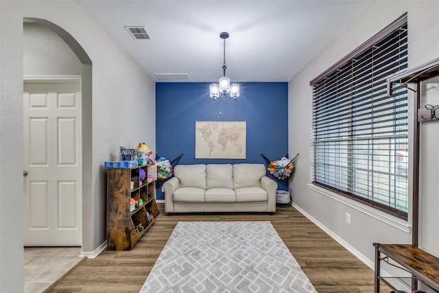 sitting room featuring wood finished floors, baseboards, visible vents, and arched walkways