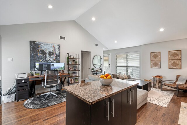 kitchen with high vaulted ceiling, visible vents, open floor plan, a kitchen island, and wood finished floors