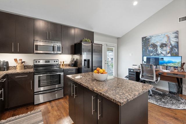 kitchen featuring lofted ceiling, appliances with stainless steel finishes, a kitchen island, visible vents, and dark wood-type flooring