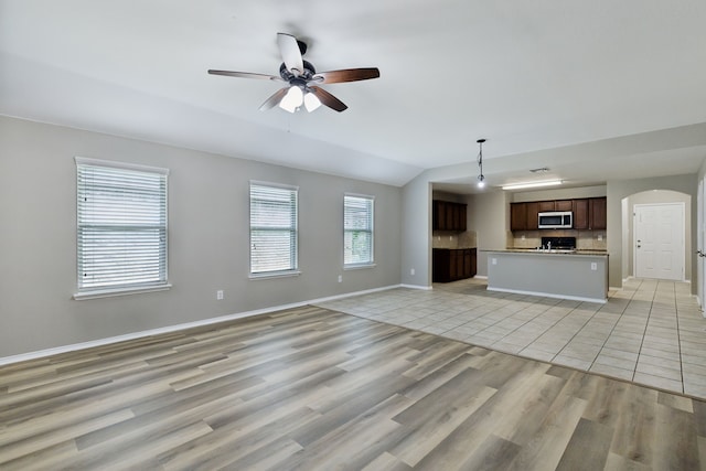unfurnished living room with light wood-style floors, a ceiling fan, baseboards, arched walkways, and lofted ceiling