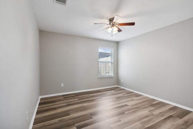 spare room featuring a ceiling fan, visible vents, wood finished floors, and baseboards