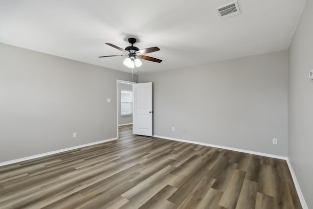 empty room with a ceiling fan, visible vents, wood finished floors, and baseboards