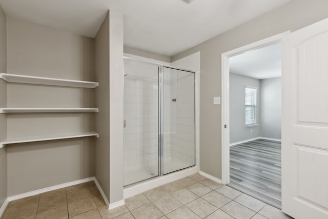 bathroom with a stall shower, tile patterned floors, and baseboards