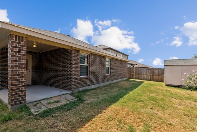 view of yard featuring a storage unit, fence, an outdoor structure, and a patio area