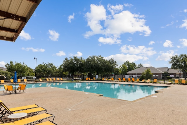 community pool with a patio and fence