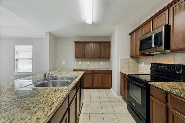 kitchen with stainless steel microwave, light tile patterned floors, backsplash, a sink, and black range with electric cooktop