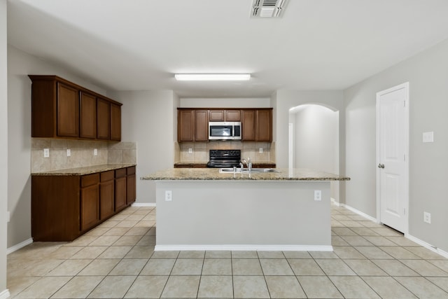 kitchen with stainless steel microwave, a sink, decorative backsplash, and visible vents