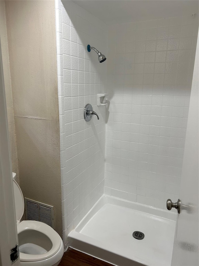 bathroom with toilet, visible vents, and a shower stall