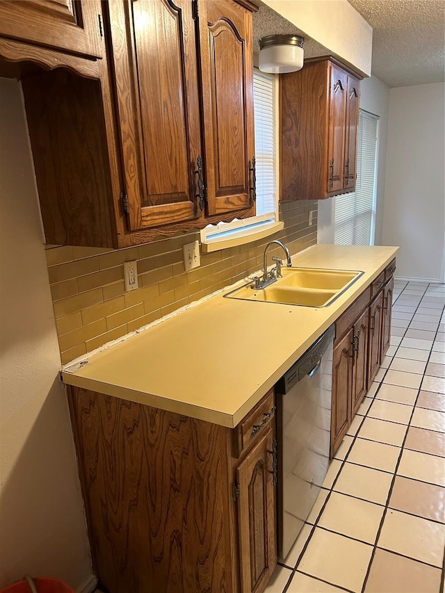 kitchen with dishwasher, a sink, a textured ceiling, and tasteful backsplash