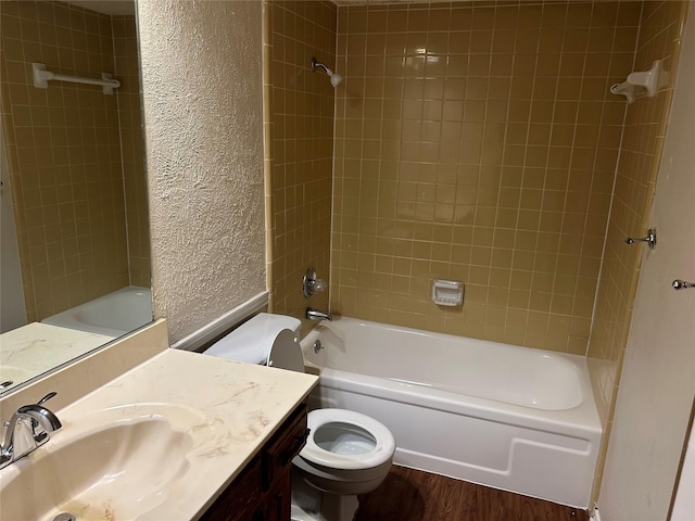 bathroom with a textured wall, toilet, shower / bath combination, wood finished floors, and vanity