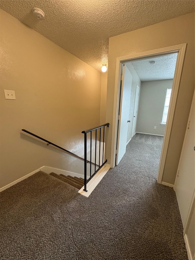 stairway featuring baseboards, a textured ceiling, and carpet flooring