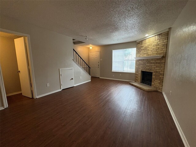 unfurnished living room featuring dark wood-style floors, stairway, a fireplace, baseboards, and a textured ceiling