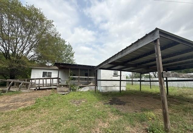 exterior space with fence, a wooden deck, and a carport