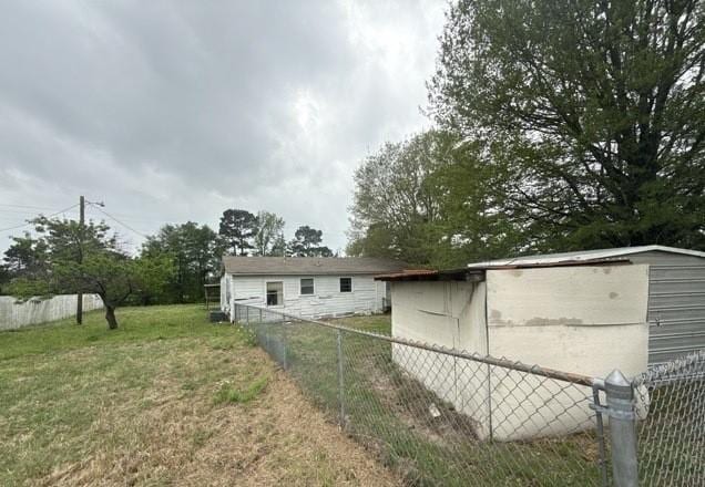 view of side of property with an outdoor structure, a yard, and fence