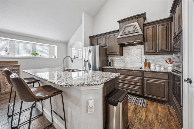 kitchen featuring tasteful backsplash, a sink, appliances with stainless steel finishes, a breakfast bar, and a kitchen island with sink