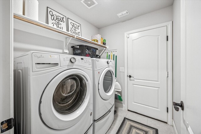 clothes washing area featuring light tile patterned flooring, visible vents, laundry area, and washing machine and dryer