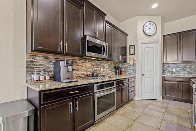 3900 Fordham St, Frisco, TX 75036 - kitchen featuring light tile patterned floors, decorative backsplash, stainless steel appliances, dark brown cabinets, and light stone countertops