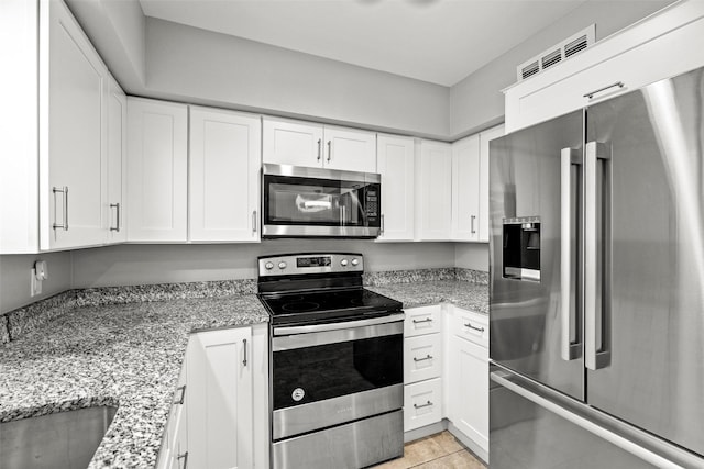 kitchen featuring light stone countertops, stainless steel appliances, light tile patterned floors, white cabinetry, and visible vents