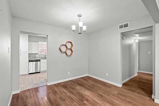 unfurnished dining area with a sink, an inviting chandelier, light wood-style floors, visible vents, and baseboards