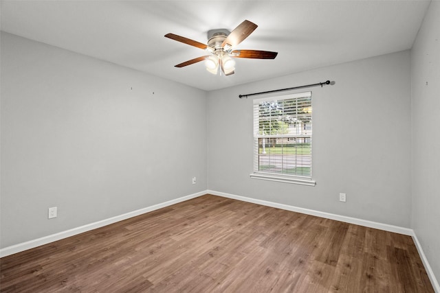spare room featuring baseboards, wood finished floors, and a ceiling fan