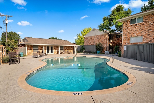 community pool with a patio, fence, and french doors