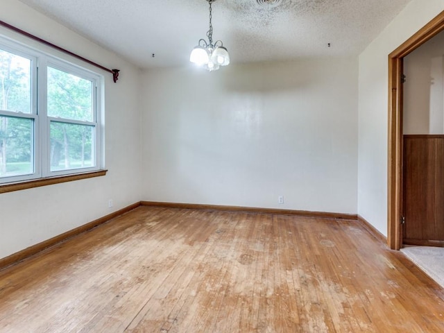 1413 Sylvan Dr, Arlington, TX 76012 - empty room with baseboards, a textured ceiling, light wood-style flooring, and a chandelier