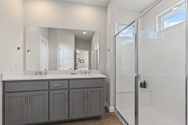 full bathroom featuring a stall shower, double vanity, a sink, and visible vents