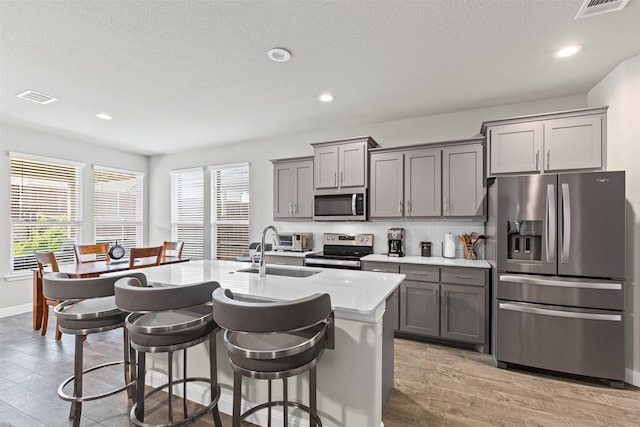 kitchen with gray cabinetry, visible vents, stainless steel appliances, and a sink