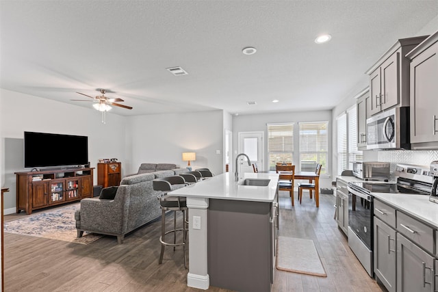kitchen featuring gray cabinetry, visible vents, stainless steel appliances, and an island with sink