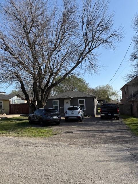 bungalow-style home featuring fence and aphalt driveway