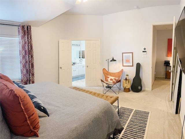 bedroom featuring baseboards, lofted ceiling, connected bathroom, and light colored carpet