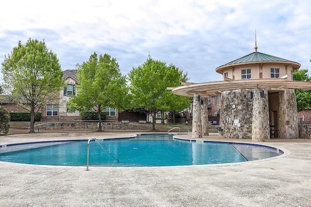 pool with a patio area and fence