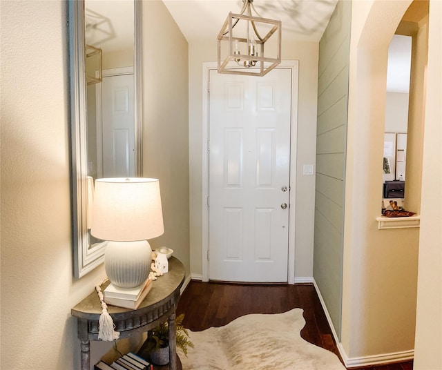 doorway featuring arched walkways, baseboards, a chandelier, and wood finished floors