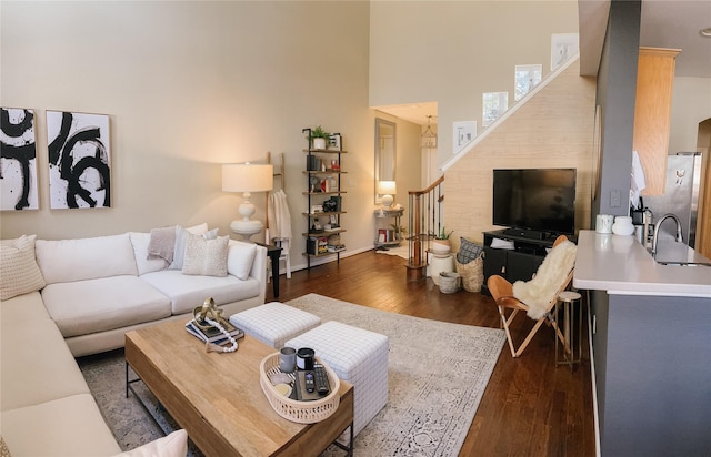 living room featuring baseboards, a high ceiling, and dark wood-style flooring