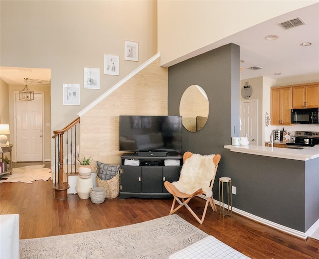 living room featuring baseboards, visible vents, wood finished floors, and stairway