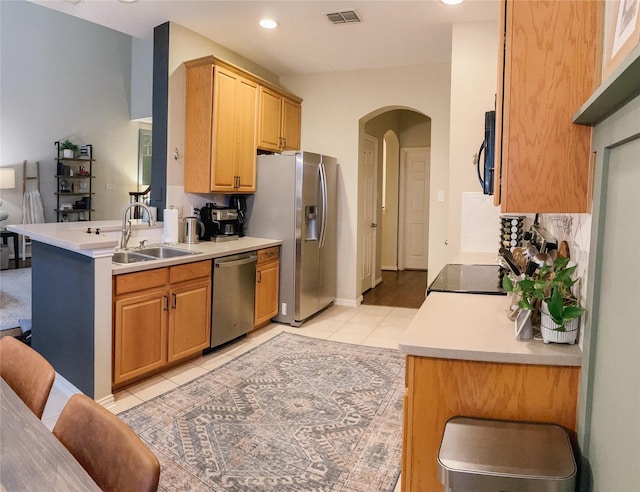 kitchen with visible vents, arched walkways, a sink, light tile patterned floors, and stainless steel appliances