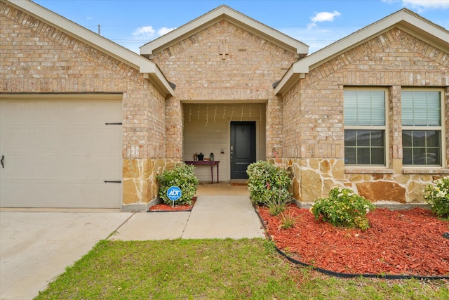 1417 Briar Hl, Denton, TX 76207 - view of exterior entry with stone siding, brick siding, and an attached garage