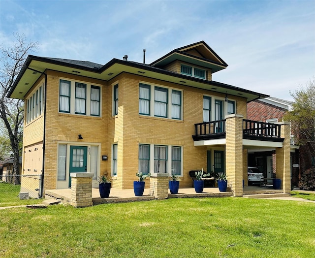back of property featuring brick siding, a balcony, and a lawn