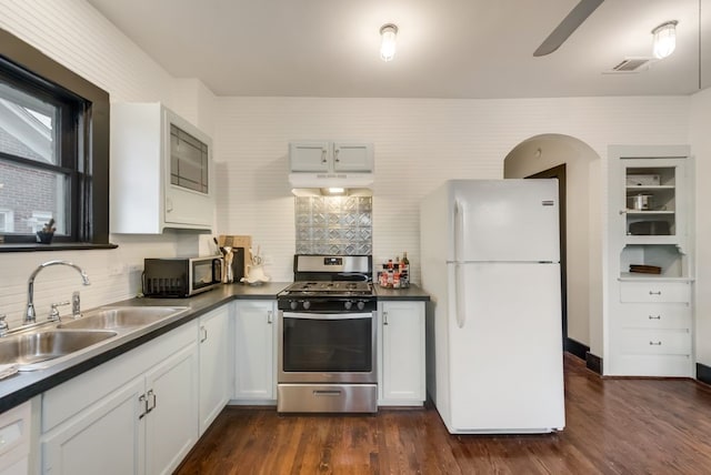 kitchen featuring dark countertops, stainless steel appliances, under cabinet range hood, and a sink