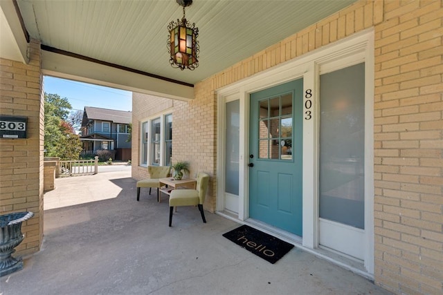 property entrance with a porch and brick siding