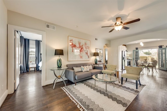 living room featuring visible vents, a healthy amount of sunlight, a ceiling fan, and arched walkways