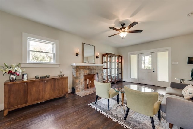 living area with a fireplace with flush hearth, ceiling fan, and dark wood finished floors