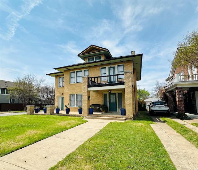 back of property featuring a chimney, brick siding, a balcony, and a lawn