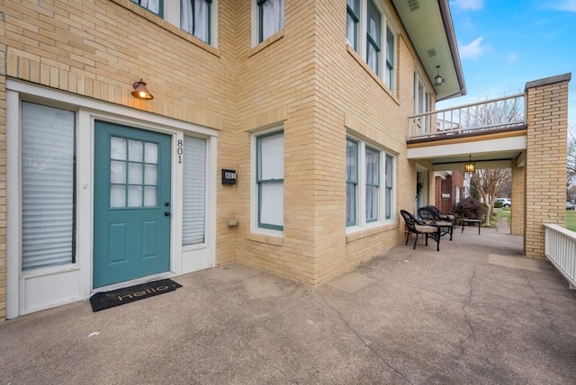 doorway to property featuring brick siding and a balcony