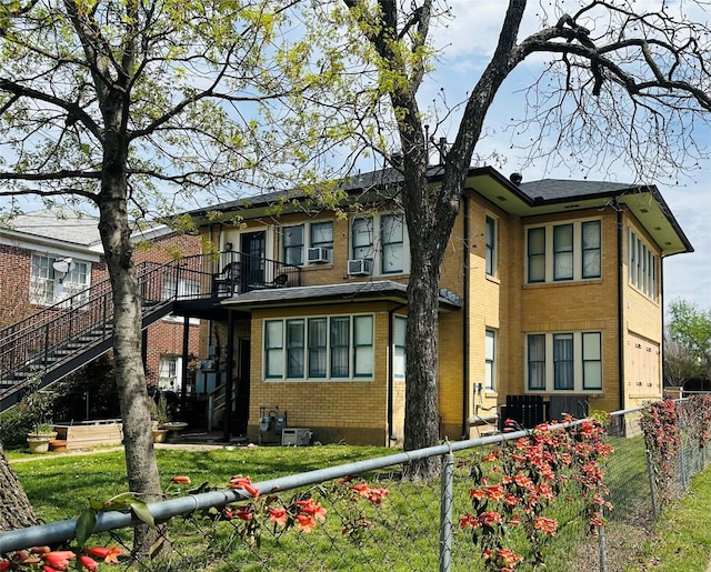 view of side of home featuring brick siding, fence private yard, stairs, and a lawn