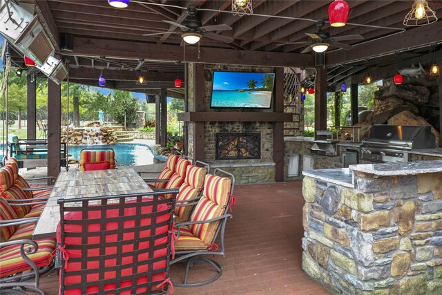 11588 Wild Rose Ln, Anna, TX 75409 - wooden terrace with area for grilling, ceiling fan, an outdoor stone fireplace, and exterior kitchen