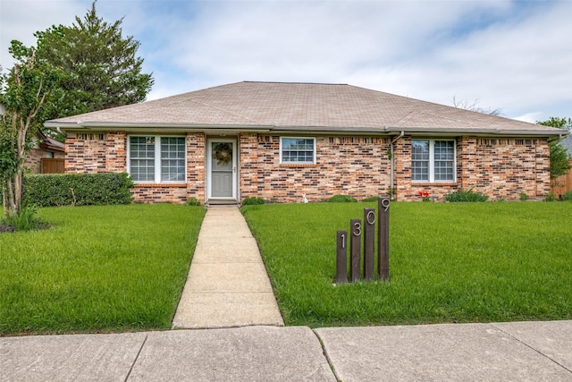 single story home featuring brick siding, a front yard, and roof with shingles